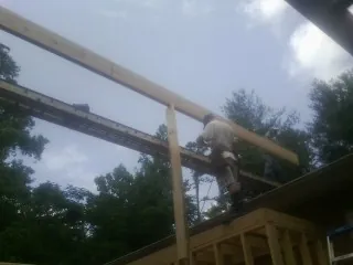 Carpenter setting a ridge beam over a new addition frame — Ice Dam Removal by Roofing Brothers in Skillman