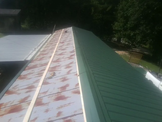 Old rusted panels beside newly installed green metal roofing — Wind Damage Roof Repair by Roofing Brothers in Skillman