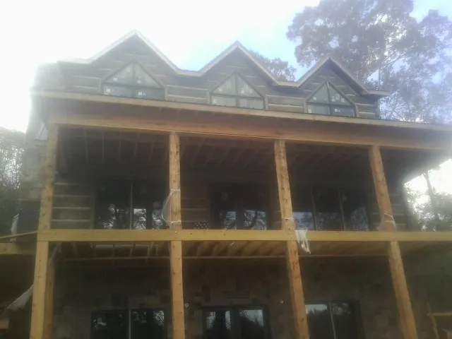 Dormers and porch framing on a large log home under construction — Roof Coating work by our crew in Skillman