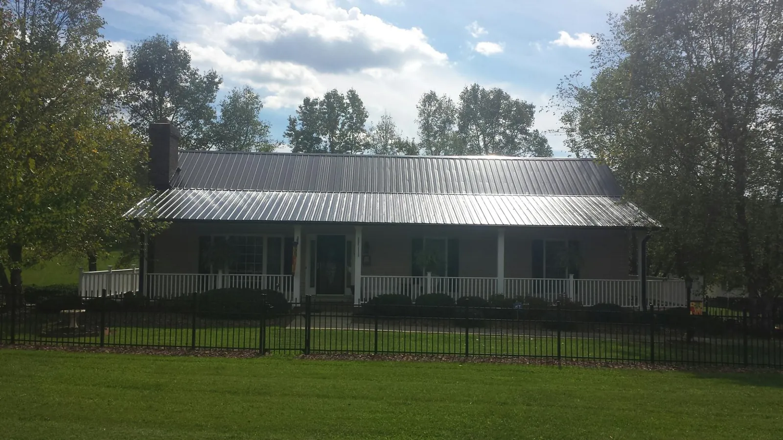 Gray metal roof on a brick ranch with a full width front porch — Gutter Guard Installation work by our crew in Skillman