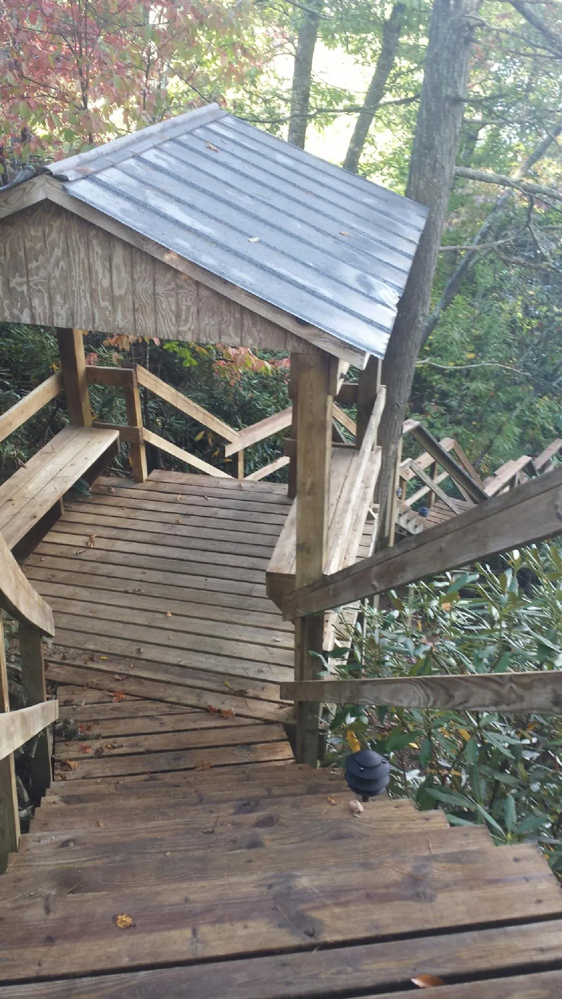 Metal roofed shelter over wooden steps on a wooded walkway — Skylight Repair & Installation work by our crew in Skillman