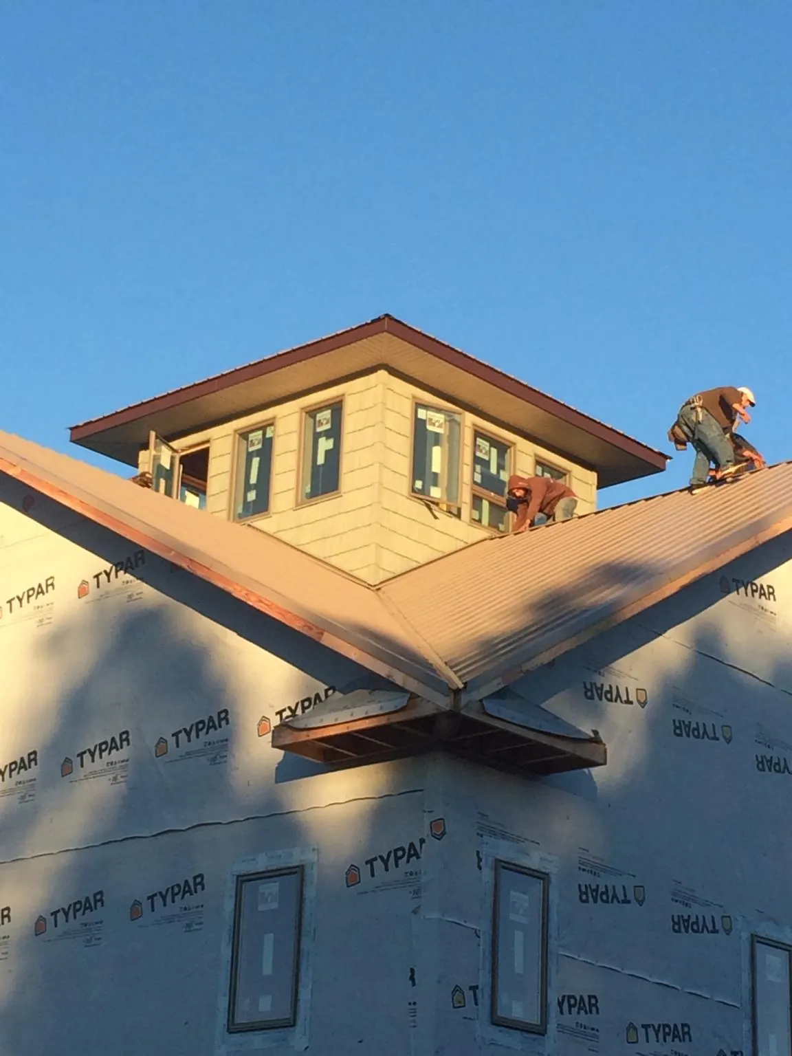 Roofers working around a rooftop cupola on a new metal roof at sunset — Roof Waterproofing in Skillman by Roofing Brothers